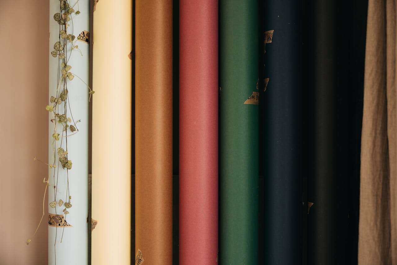 gallery-1 Vertical arrangement of colored paper rolls with dried vine accent, artistic composition.